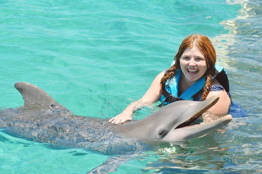 a woman swimming with a dolphin in Isla Mujeres